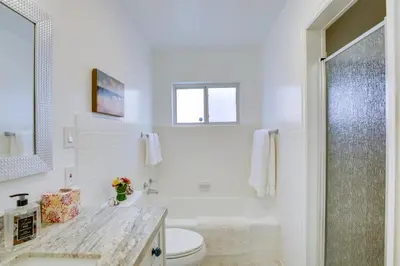 a white bathroom with a toilet and a shower at Oceanfront Escape Steps to Imperial Beach! in Imperial Beach