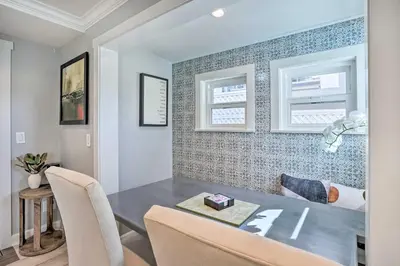 a dining room with a table and two windows at Luxe Laguna Home with Ocean View Walk to Beach in Laguna Beach