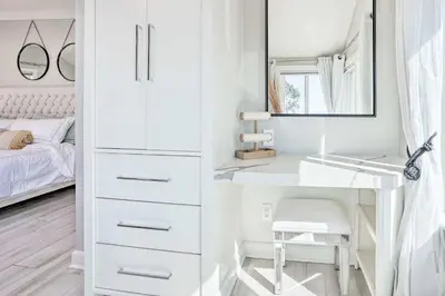 a white bedroom with a vanity and a mirror at Luxe Laguna Home with Ocean View Walk to Beach in Laguna Beach