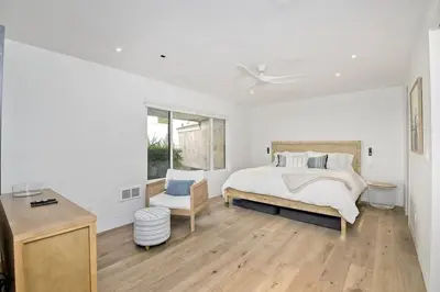 a white bedroom with a bed and a chair at Oceanfront Luxury, Fully Remodeled, Five-Star in Solana Beach
