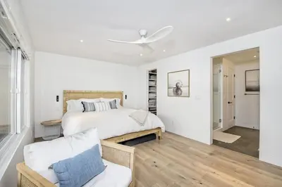 a white bedroom with a bed and a chair at Oceanfront Luxury, Fully Remodeled, Five-Star in Solana Beach