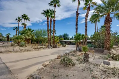a driveway with palm trees in front of a house at Borrego Springs Retreat with Pool and Mtn Views in Borrego Springs