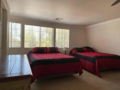 a bedroom with two beds with red sheets and windows at Wondrous Stays in Temecula