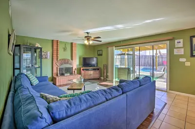 a living room with a blue couch and a tv at Breeze By the Pool Chula Vista Home with Game Room in Chula Vista