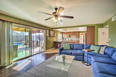 a living room with a blue couch and a ceiling fan at Breeze By the Pool Chula Vista Home with Game Room in Chula Vista