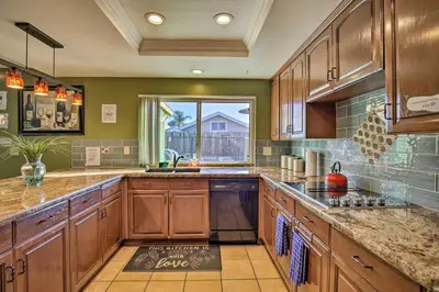 a large kitchen with wooden cabinets and a window at Breeze By the Pool Chula Vista Home with Game Room in Chula Vista