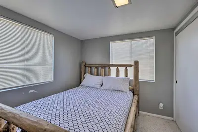 a bedroom with a wooden bed with two windows at Escondido Hilltop Home with Deck and Views! in Escondido