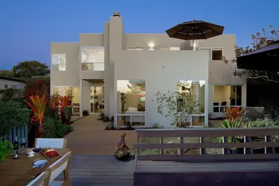a large white house with a table and an umbrella at Grandview Getaway, Luxury 4BR, Ocean View, Fire Pit in Encinitas