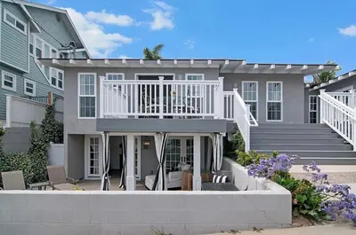 a large house with a white deck and stairs at Remodeled Beach Bungalow, Block to the Beach in Carlsbad