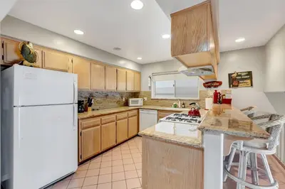 a kitchen with wooden cabinets and a white refrigerator at OCEAN FRONT - STUNNING VIEWS- VACATION PARADISE!! in Dana Point
