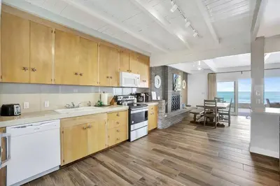 a large kitchen with wooden cabinets and a dining room at ON THE SAND!! Private Beach! OCEAN FRONT HOT TUB!! in Dana Point