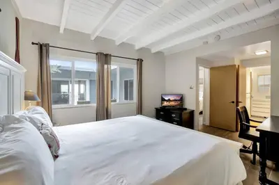 a bedroom with a large white bed and a television at ON THE SAND!! Private Beach! OCEAN FRONT HOT TUB!! in Dana Point