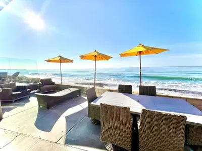 a table with chairs and umbrellas on the beach at ON THE SAND!! Private Beach! OCEAN FRONT HOT TUB!! in Dana Point