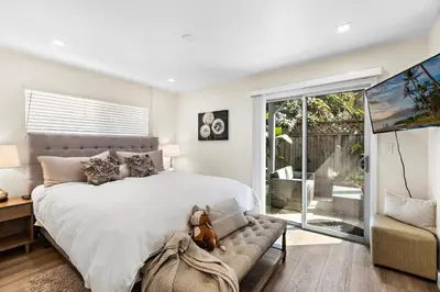 a bedroom with a large bed and a sliding glass door at Amazing New & Water Vu/Balboa Peninsula! EV charge in Newport Beach