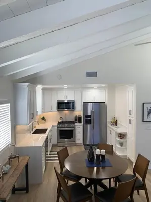 a kitchen with a table and chairs and a refrigerator at Amazing New & Water Vu/Balboa Peninsula! EV charge in Newport Beach
