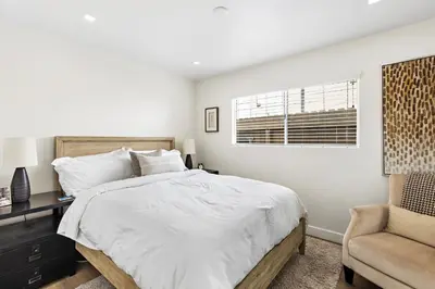 a white bedroom with a bed and a chair at Amazing New & Water Vu/Balboa Peninsula! EV charge in Newport Beach