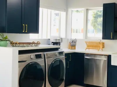 a kitchen with blue cabinets and a washing machine at Village District! Cleo Beach! 5 Min Walk to DTWN! in Laguna Beach