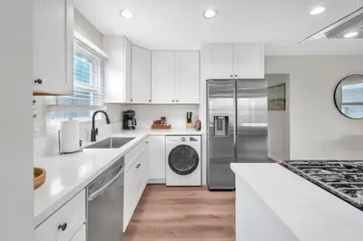 a kitchen with white cabinets and a stainless steel refrigerator at Tower 9 #1 in Oceanside