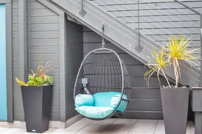 a swing hanging from a porch with two potted plants at Tower 9 #4 in Oceanside