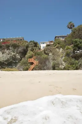 a beach with a wooden object on a hill at OCEAN FRONT Beach HOUSE! Private Stairs to SAND! in Laguna Beach