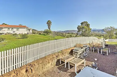 a fence with tables and chairs in front of a house at Garden, Gazebo and Fire Pit Fallbrook Home! in Fallbrook