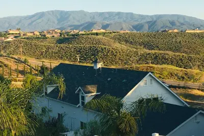 a white house on a hill with mountains in the background at Ask about the 100 Dollar Taco Caterer for 10 and Free Wine Tickets in Temecula