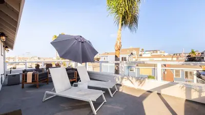 a patio with two chairs and an umbrella on a balcony at Sea Sight by AvantStay Walk to Newport Beach in Newport Beach