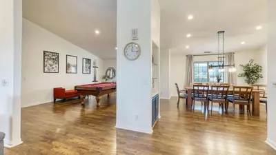 a dining room and living room with a clock on a wall at 5-Acre Hilltop Estate w Resort Pool Game Room Le Grand Bleu by AvantStay in Temecula