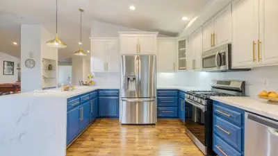 a kitchen with blue cabinets and a stainless steel refrigerator at 5-Acre Hilltop Estate w Resort Pool Game Room Le Grand Bleu by AvantStay in Temecula