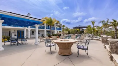 a patio with chairs and a table and a building at 5-Acre Hilltop Estate w Resort Pool Game Room Le Grand Bleu by AvantStay in Temecula