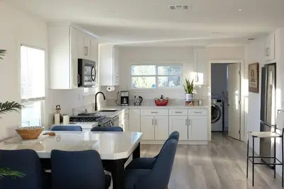 a kitchen with white cabinets and a table with blue chairs at Aviation Landing in Fallbrook
