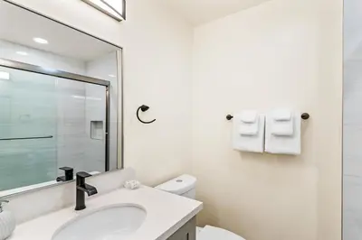 a white bathroom with a sink and a mirror at 4912 Seashore A Lower in Newport Beach