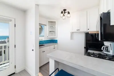 a kitchen with white cabinets and a view of the ocean at Pacific Villas in Oceanside