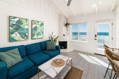 a living room with a blue couch and some windows at Pacific Villas in Oceanside