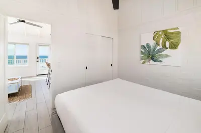 a white bedroom with a bed and a window at Pacific Villas in Oceanside