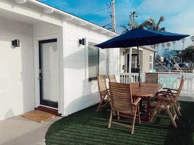 a table and chairs with an umbrella on the back of a house at Beach house in the heart of balboa peninsula in Newport Beach