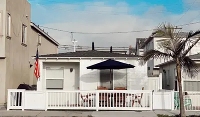 a white house with a white fence and an umbrella at Beach house in the heart of balboa peninsula in Newport Beach