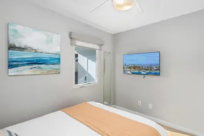 a bedroom with a bed and two paintings on the wall at Newly Renovated 3BR Modern Apt in Heart of Ocean Beach in San Diego