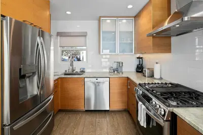 a kitchen with a stainless steel refrigerator and wooden cabinets at Newly Renovated 3BR Modern Apt in Heart of Ocean Beach in San Diego
