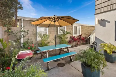 a picnic table with an umbrella and a bench at Modern Newly Renovated 2BR Apt in Heart of Ocean Beach in San Diego