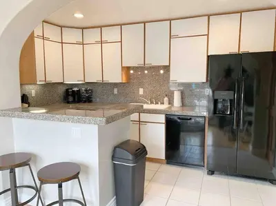 a kitchen with white cabinets and a black refrigerator at Steps To The BEST Beach . Surf . Spa . Main Street in Encinitas
