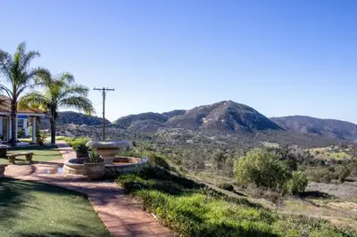 a house with a view of a mountain at Private Home on 10 Acres - Heated Salt Pool & Jacuzzi, Mountain & City Views, Horseshoes, Basketball, BBQ, Golf Putting, Foosball, Croquet, Bose Stereo, White Cotton Bedding - Hilltop Hacienda, Pool Heat Optional in Jamul