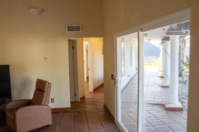 a living room with a glass door and a chair at Private Home on 10 Acres - Heated Salt Pool & Jacuzzi, Mountain & City Views, Horseshoes, Basketball, BBQ, Golf Putting, Foosball, Croquet, Bose Stereo, White Cotton Bedding - Hilltop Hacienda, Pool Heat Optional in Jamul