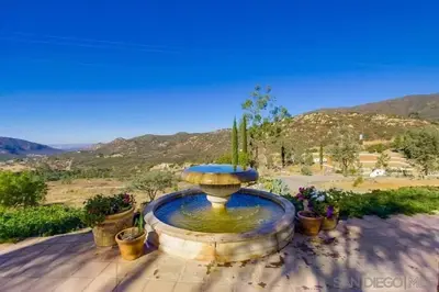 a large fountain in a yard with potted plants at Private Home on 10 Acres - Heated Salt Pool & Jacuzzi, Mountain & City Views, Horseshoes, Basketball, BBQ, Golf Putting, Foosball, Croquet, Bose Stereo, White Cotton Bedding - Hilltop Hacienda, Pool Heat Optional in Jamul