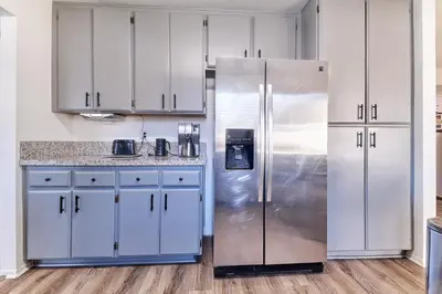 a kitchen with white cabinets and a stainless steel refrigerator at Entire Mountain Oasis Home in Hemet
