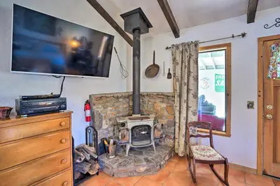 a living room with a stone fireplace and a tv at Cozy Story Book Barn Cottage with Scenic View in Julian