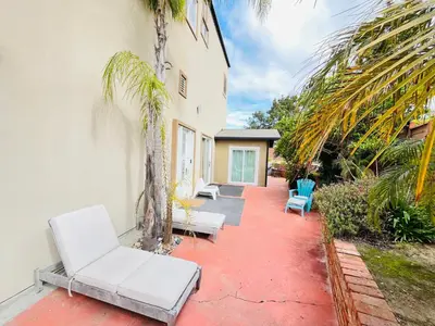a patio with white chairs and palm trees next to a building at Private Room3 Own Entry Shared Bath One Guest Walk to UCSD in San Diego