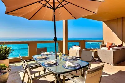 a dining table with an umbrella on a patio at Celebrity Oceanfront Estate in San Diego