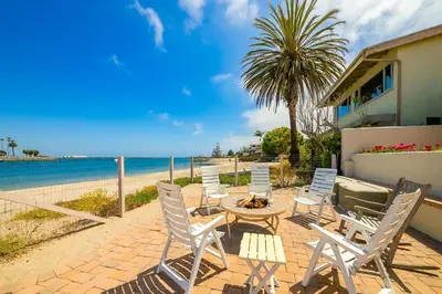 a patio with chairs and a table next to the beach at On The Beach Casa in San Diego