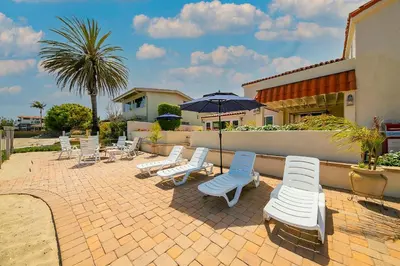 a group of chairs and umbrellas on a brick patio at On The Beach Casa in San Diego